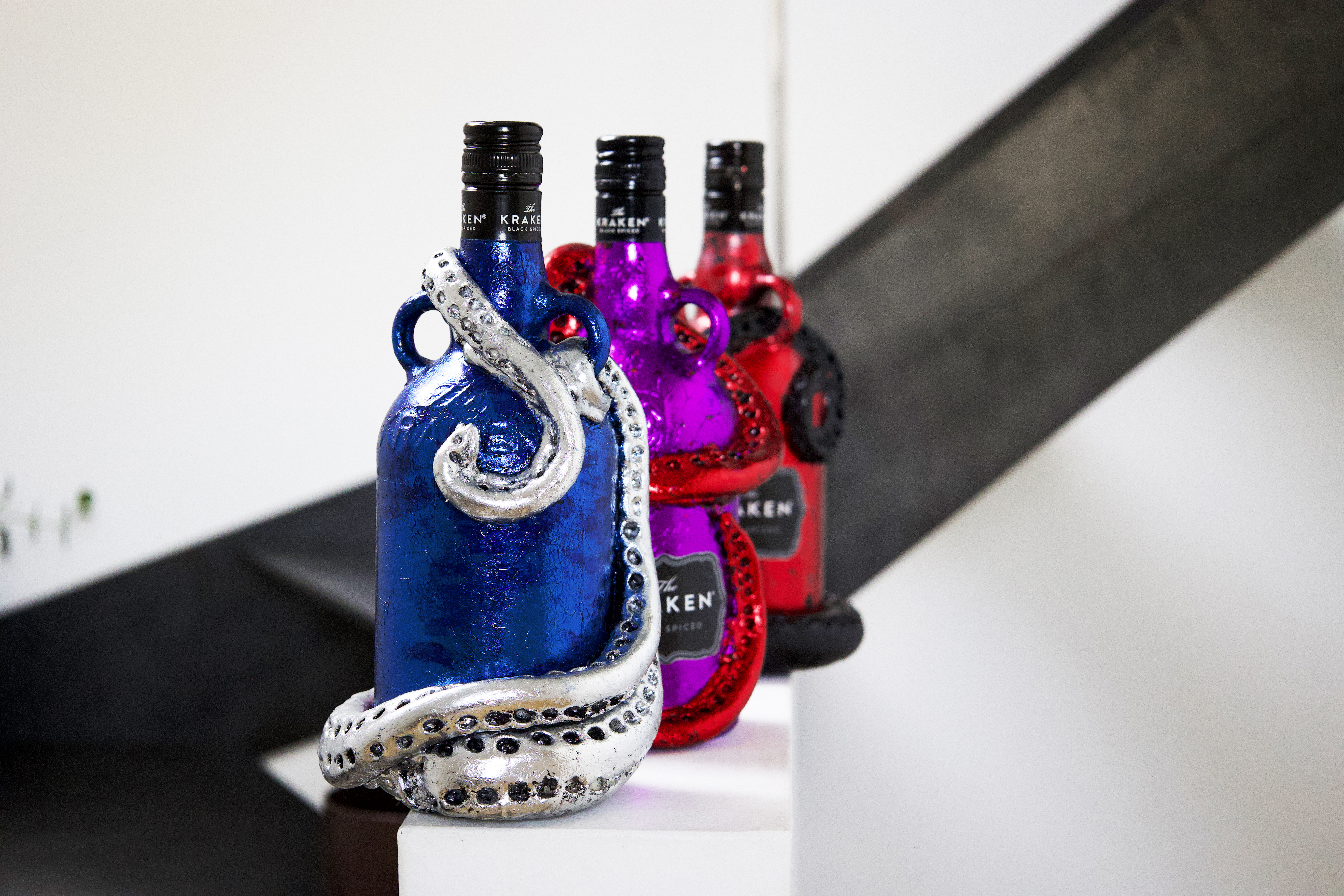 Three colorful Kraken rum bottle sculptures arranged on a staircase.