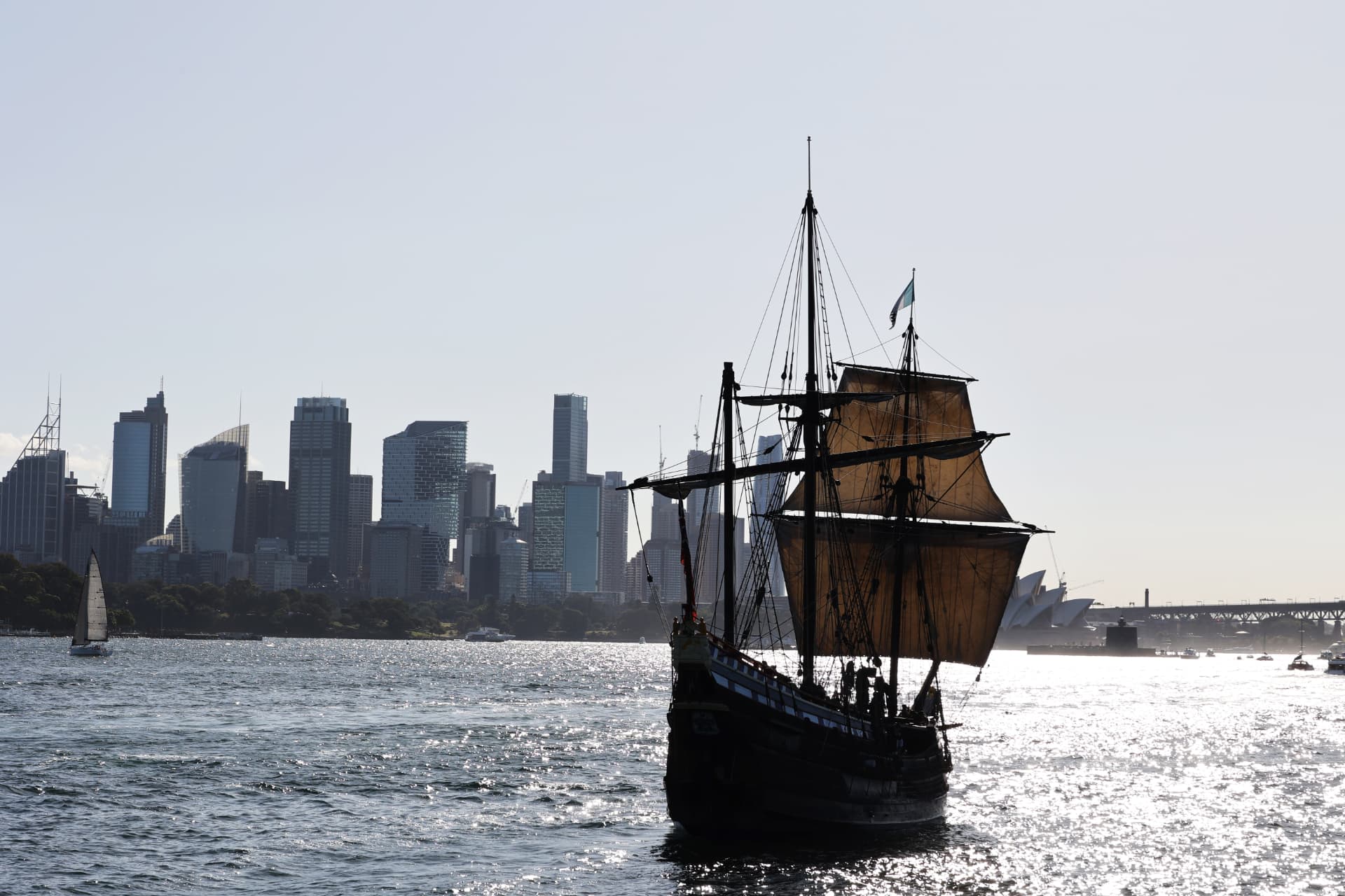 A tall ship sailing on Sydney Harbour with the Sydney skyline, Opera House and Harbour Bridge behind