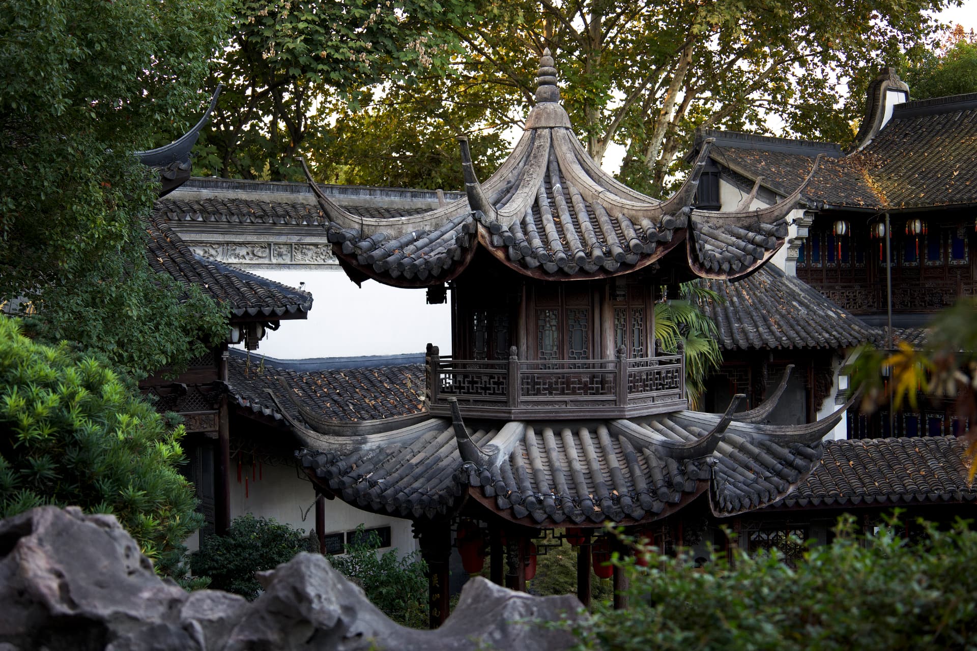 Traditional Chinese garden architecture with layered curved tile roofs and wooden pavilions surrounded by trees in Hangzhou, China