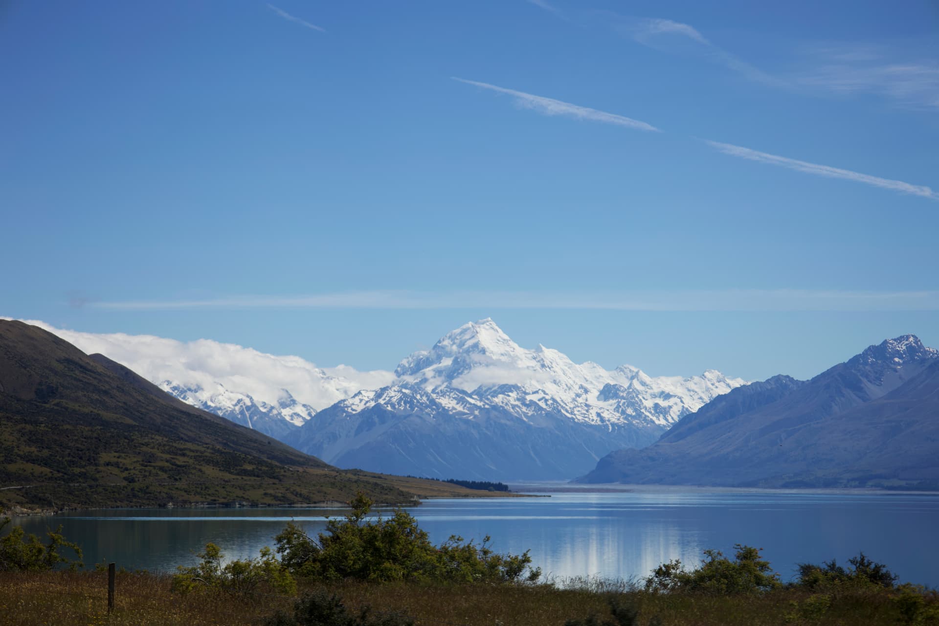 Snow-capped Mount Cook reflected in a calm lake beneath a clear blue sky
